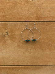 Silver hoop earrings with beads on a wooden surface