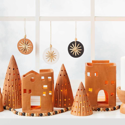 Decorative ceramic pieces resembling houses and trees on a white surface with a light background.