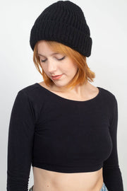 Person wearing a black beanie and black long-sleeve top on a white background