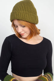 Woman wearing a green knitted beanie and gloves on a white background