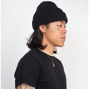 Person wearing a black knit beanie and black t-shirt on a white background