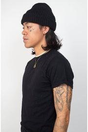 Person wearing a black beanie and black t-shirt on a white background