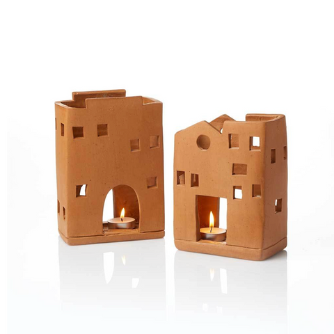 Two terracotta candle holders shaped like small buildings on a white background