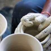 Person shaping clay on a potter's wheel with a blurred background