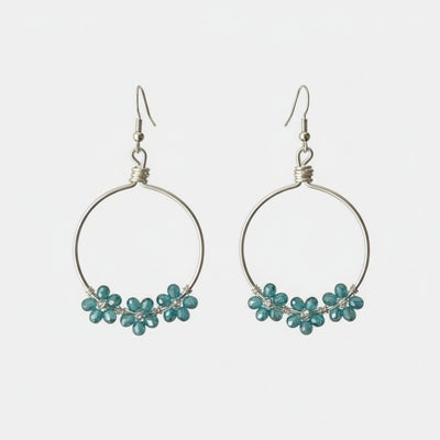 Close-up of a person wearing hoop earrings with small embellishments, indoors.