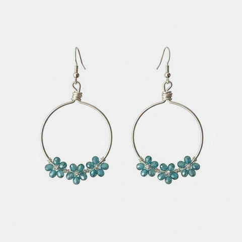 Close-up of a person wearing hoop earrings with small embellishments, indoors.