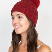 Woman wearing a red knitted beanie with a pom-pom on a white background
