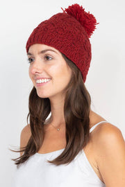 Woman wearing a red knitted beanie with a pom-pom on a white background