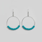 Two metal hooks with turquoise beads on a wooden surface