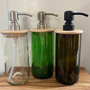 Three glass bottles with wooden lids and metal pumps on a wooden surface.