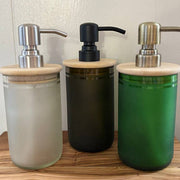 Three soap dispensers with wooden caps on a wooden surface.