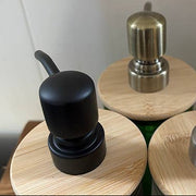 Three cylindrical containers with wooden lids and metallic tops on a white background