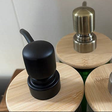 Three cylindrical containers with wooden lids and metallic tops on a white background
