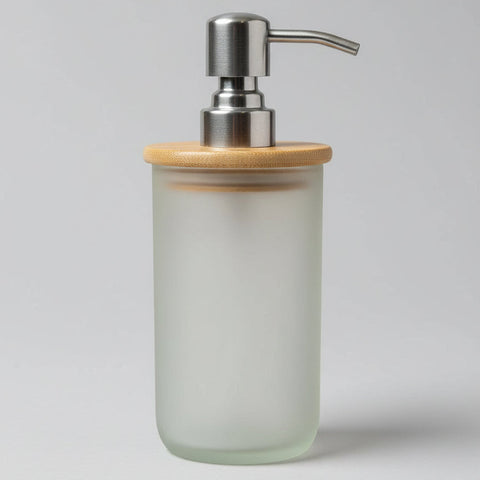 A handmade soap dispenser made of frosted glass with a bamboo lid on top, placed on a wooden surface.