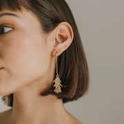 Close-up of a woman wearing gold earrings with a neutral background