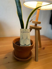 Potted plant with a card labeled 'do good shop' on a wooden surface next to a lamp.