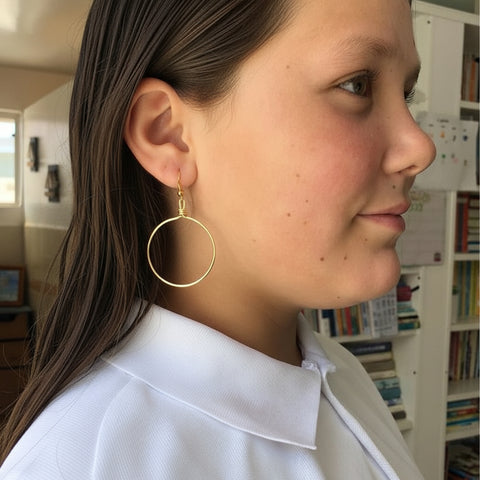 Person wearing gold hoop earrings with a blurred background