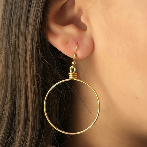 Close-up of a person wearing silver hoop earrings with a bookshelf in the background