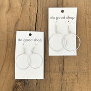 Pair of silver hoop earrings on 'do good shop' cards against a wooden background