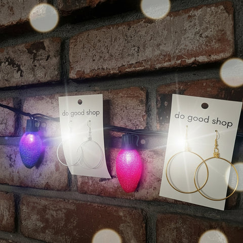 Earrings on cards with 'do good shop' branding against a brick wall background.