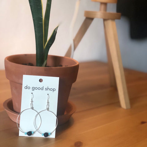 Earring card with earrings on a wooden surface next to a potted plant