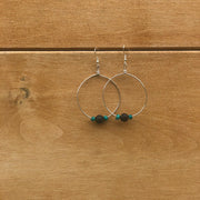 Silver hoop earrings with beads on a wooden surface