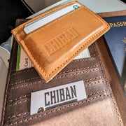 Brown leather wallet with 'Chiban' branding, passport, and cards on a table.