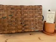 Woven wooden board with hanging earrings on a wooden surface