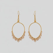 Gold hoop earring with small beads worn by a person