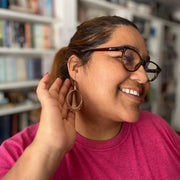 Woman wearing glasses and a pink shirt, smiling in a library setting