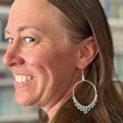 Woman wearing hoop earrings with a blurred bookshelf background