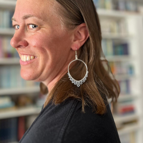 Close-up of a person wearing gold hoop earrings with small embellishments.