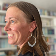 Woman wearing a silver hoop earring in a library setting