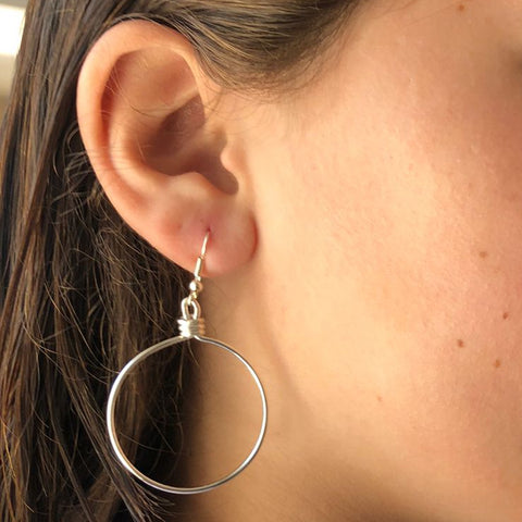 Close-up of a person wearing hoop earrings with a blurred background
